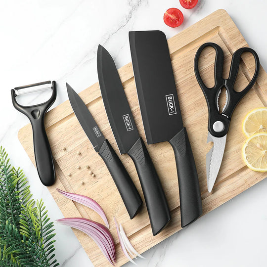 Set of black kitchen knives and tools on a wooden cutting board with vegetables.