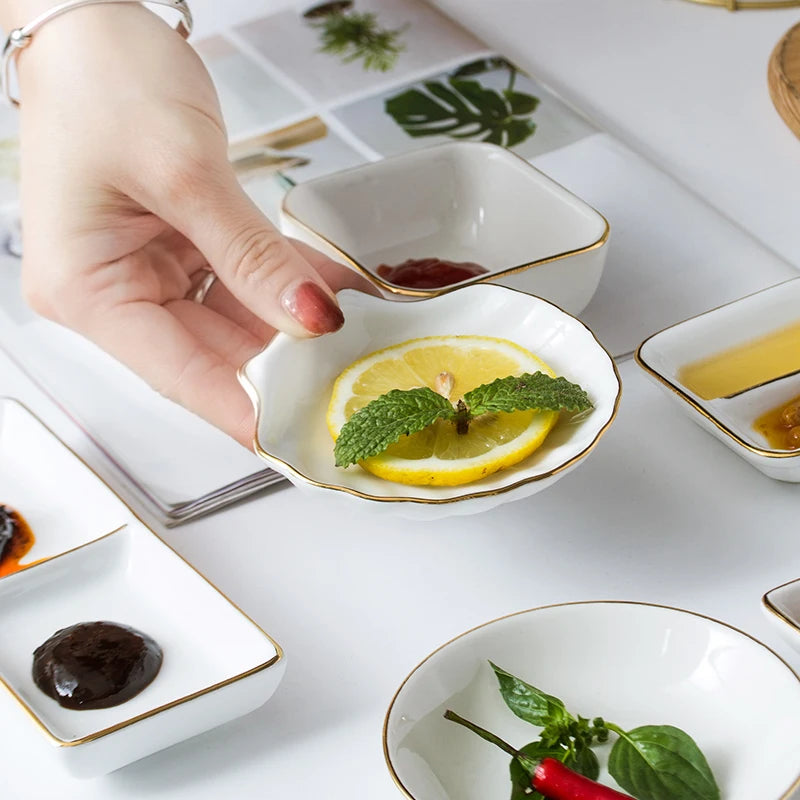 Hand holding a small dish with lemon and mint leaves on a table with various dishes.
