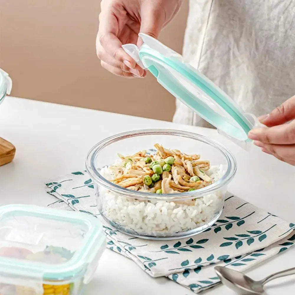 Person using a silicone lid to cover a glass bowl of food on a table.