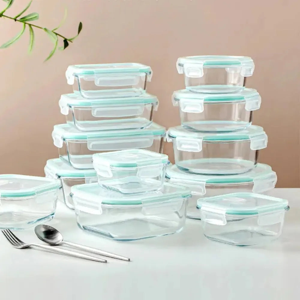 Set of glass food storage containers with lids on a light surface.