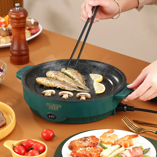 Person using chopsticks to cook fish on a portable electric grill with various dishes around.