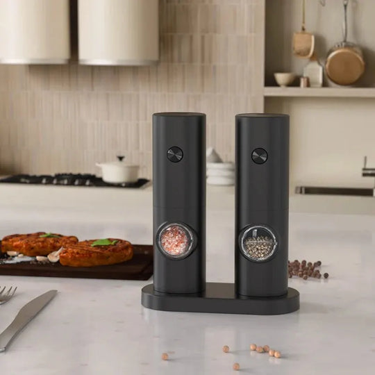 Black salt and pepper shakers on a kitchen counter with a blurred background