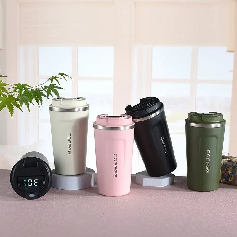 Four colorful insulated coffee tumblers on a table with a plant in the background.